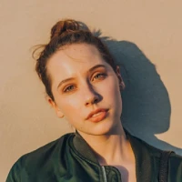 Portrait of a young woman with hair in a bun wearing a dark green top